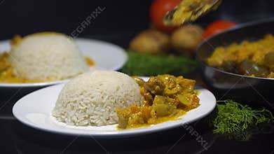 Tasty chicken curry, Indian dish with steamed rice. Chef adding chicken curry to the steamed rice, plate on the black
