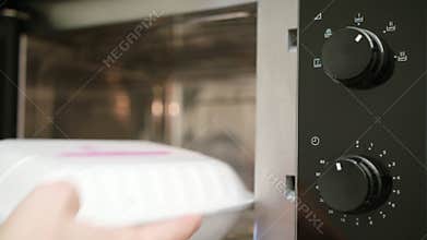 A Hand Taking a Container out of Microwave Oven