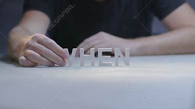 Male hands making composition word when by letters on gray background