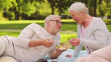 Senior couple eating salad at picnic in park