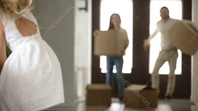 Excited couple with kids and boxes moving in new house