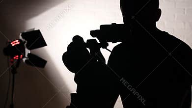 Silhouette of Cameraman Working Behind the Scenes in Film Studio