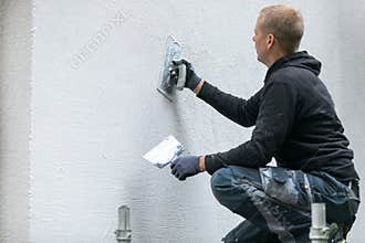 Construction worker putting decorative plaster on house exterior
