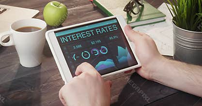 Checking interest rates data using tablet computer at desk