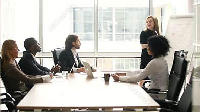 Businesswoman giving presentation to multi-ethnic colleagues at meeting in boardroom