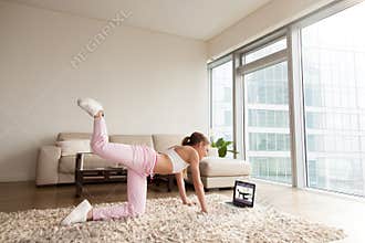 Young sporty woman working out at home, online fitness training