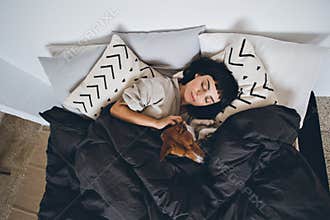 Woman and dog sleep in bed