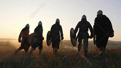 Warriors vikings going and stoping in field and look at beautiful sunset.