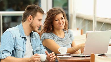 Couple talking about laptop content in a bar