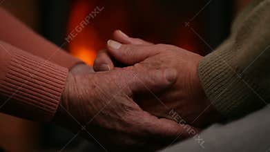 Senior hands of woman and man in front of the fireplace - comforting each other at old age