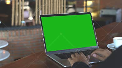 Hand typing on laptop keyboard showing green screen, 4k