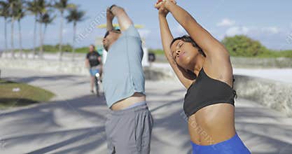 Sportive couple stretching in sunlight