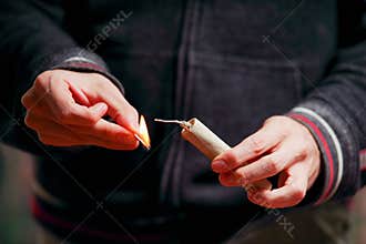 Close up of man hand lighting up a firecrackers in a burred background