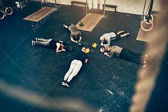Group of fit people planking together on a gym floor