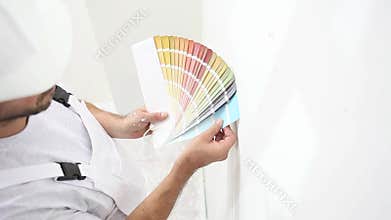 Painter man at work choice color with swatches samples, wall painting concept, white copy space