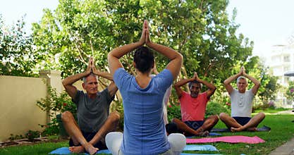 Trainer and seniors performing yoga in garden 4k