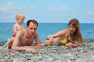 Family on sea coast build pyramid