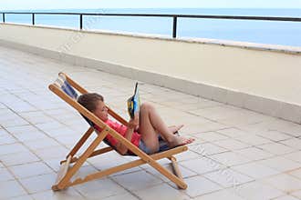 Boy reads in lounge on veranda