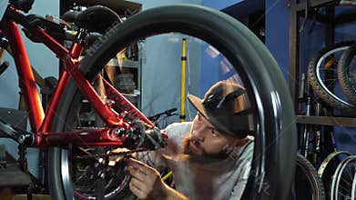 A young mahanic fixing a bicycle wheel in her repair workshop
