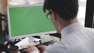 Young man works with pc with green screen and keyboard . 4K
