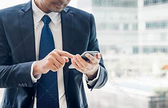 Close up hand of businessman using mobile phone near office wind