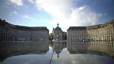 Tourists walking near mirror fountain at Place de la Bourse in Bordeaux, France