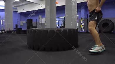 Young man flipping tyre while exercising.