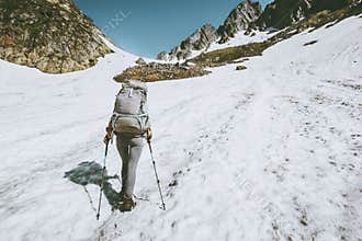 Alpinist woman with backpack climbing to the top of mountain