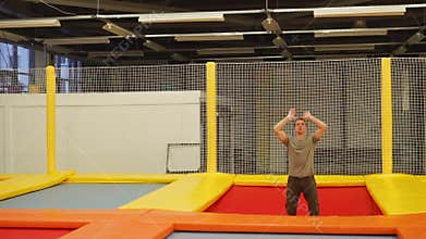 Adult sportsman is jumping on a trampoline in a gymnastic hall