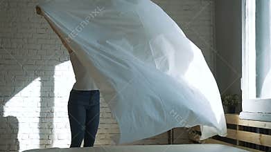 Young housewife making bed ungraded