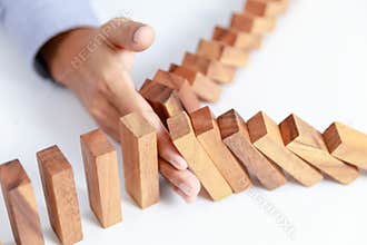 Businessman hand protect wooden toy block from danger and fall