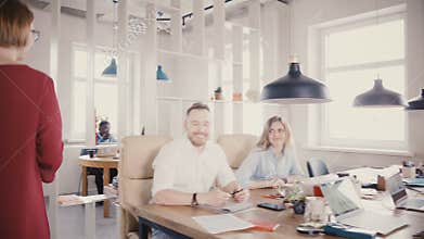 Camera follows attractive female boss enter office, talk to colleagues, smile, motivate workers in trendy office 4K.