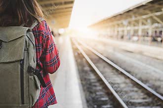 Young Asian woman backpacker traveler walking alone at train station platform with backpack.