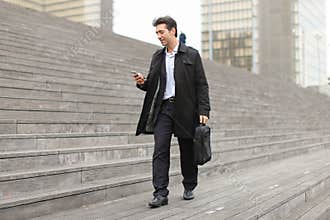 business man walking using smartphone to watch photos.