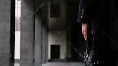 Young businessman lawyer in classic costume hold case with documents and walk slow motion close up. He walks down the