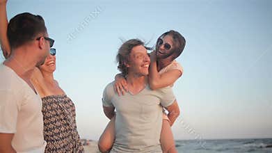 Two Couples Laughing near the Sea During Summer Time. Outdoors Portrait of Happy Young Group of Friends Enjoying Beach
