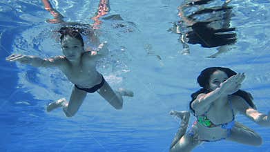 Boy and girl dive in swimming pool, slow motion