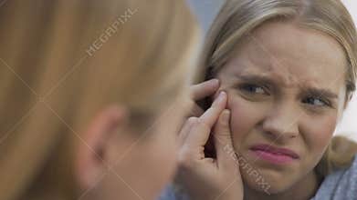 Upset girl popping blackhead with dirty hands, unhygienic procedures, acne