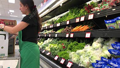 Motion of produce clerk stocking vegetable for sale inside Walmart