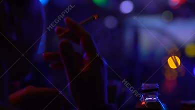 Smoking clubber relaxing cigarette in night club, party atmosphere, chill out