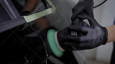 Crop unrecognizable man standing and polishing car trunk in garage