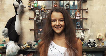 Lovely cute girl with pretty smile looking at camera. Old garden with vintage toys location. 4k footage. Close-up