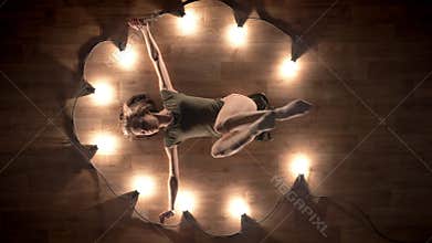 Silhouette of young girl ballerina is dancing and laying on wooden floor, lights around, ballet concept, movement