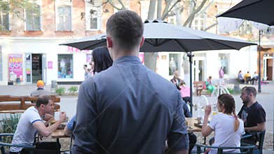Service staff of cafe pays attention to luxurious girl during work on open air