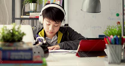 Young teenage student listen to music from tablet computer and doing homework at home, Dolly move left to right.