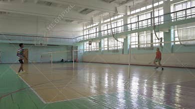 Two Guys Play Badminton at the School Sports Hall