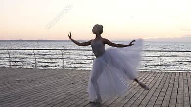 Young beautiful ballerina dressed in white tutu dancing gracefully on her pointe ballet shoes. Jumping, performing