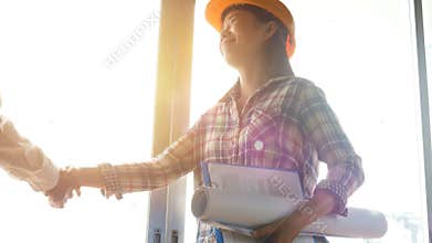 4K. happy Asian woman engineer as construction workers with blueprint and contract in hand with protective yellow helmet