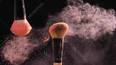 Concept of cosmetics and beauty. Make-up brushes with pink powder explosion on black background