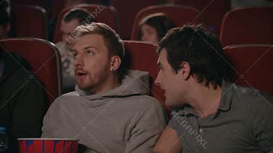 Friends wathcing movie in cinema. Man preventing to friends watching film
